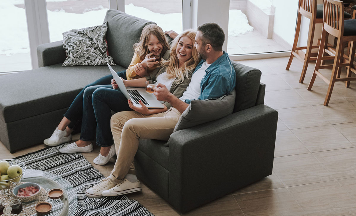 Happy family sitting on couch and watching videos on laptop 1